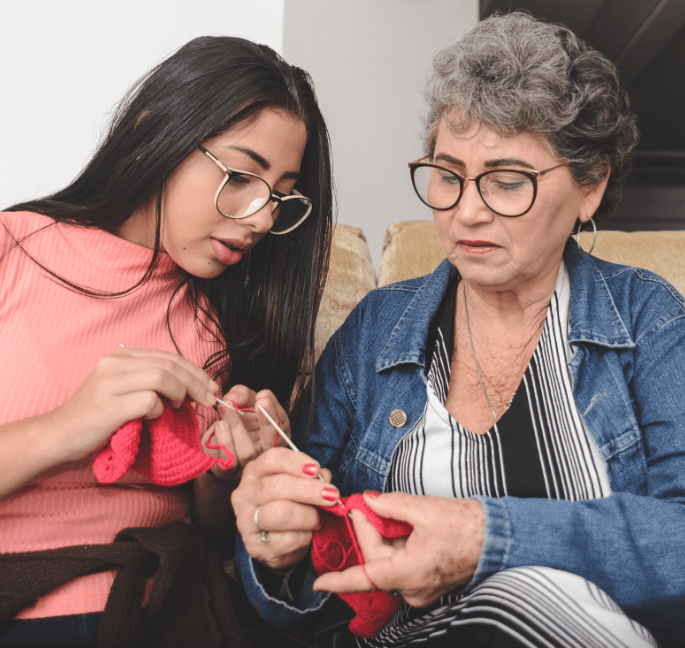 Volunteer and elderly patient knitting together